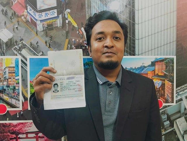 A Discovery applicant holding his passport open at the Japan visa page