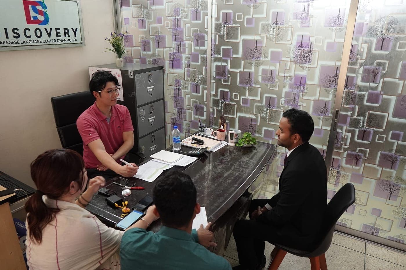 A counseling session at the Discovery center in Dhanmondi, with the center's nameplate on the wall behind the desk